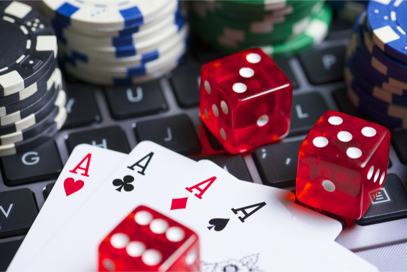 Casino chips, cards and dice stacking on a laptop