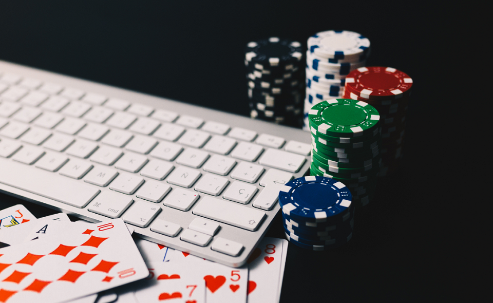 poker chips and cards surrounding a computer keyboard