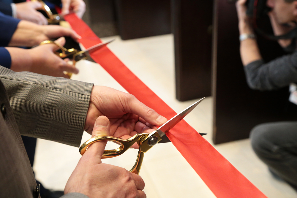 cutting of ceremonial red ribbon indicating a launch