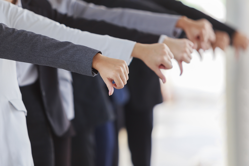 A row of people displaying thumbs down