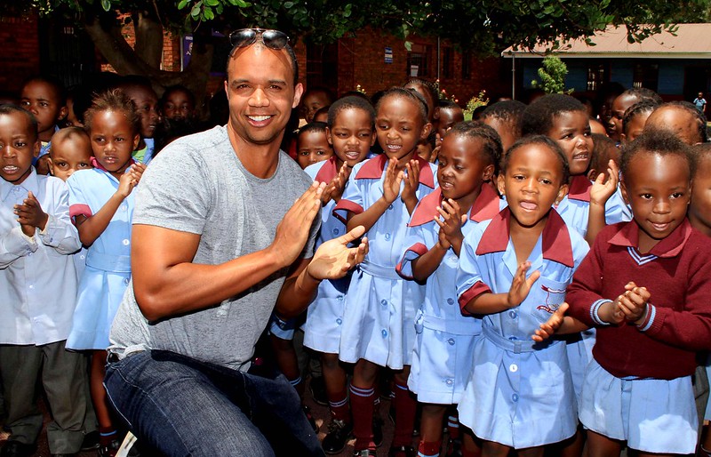 Poker Player Phil Ivey poses with children singing